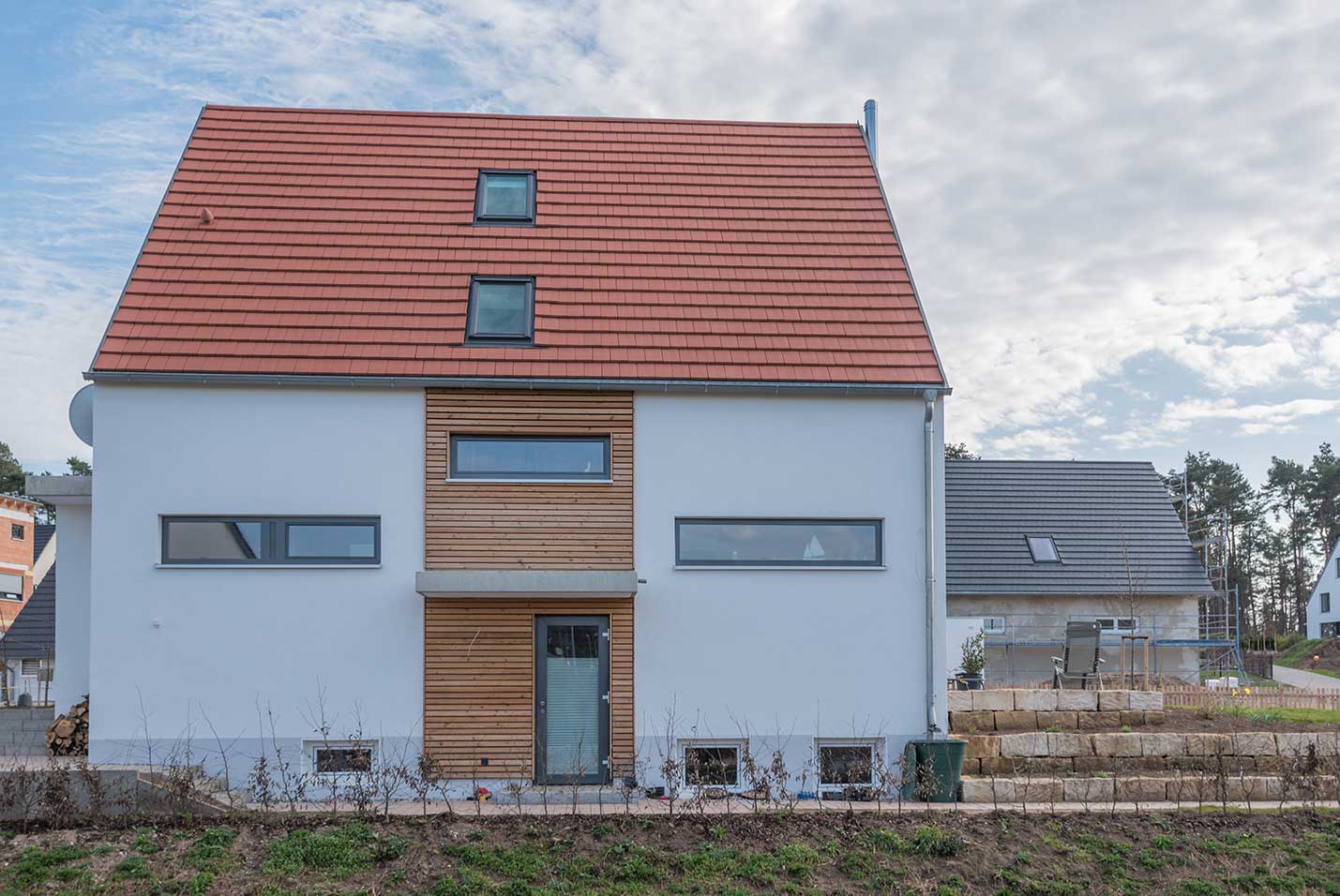 Durch die anthrazitgraue Farbe und die horizontal liegende Form der Fenster wirkt die Fassade des Hauses modern und gradlinig.