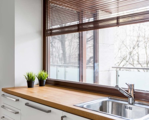 Kunststofffenster in einer dunklen Holzoptik ergänzen eine moderne Küche optimal.