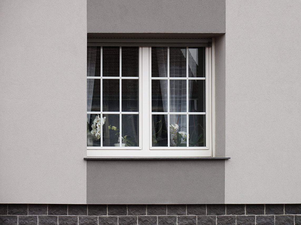 Fenster mit Fensterbank vor grauer Hauswand